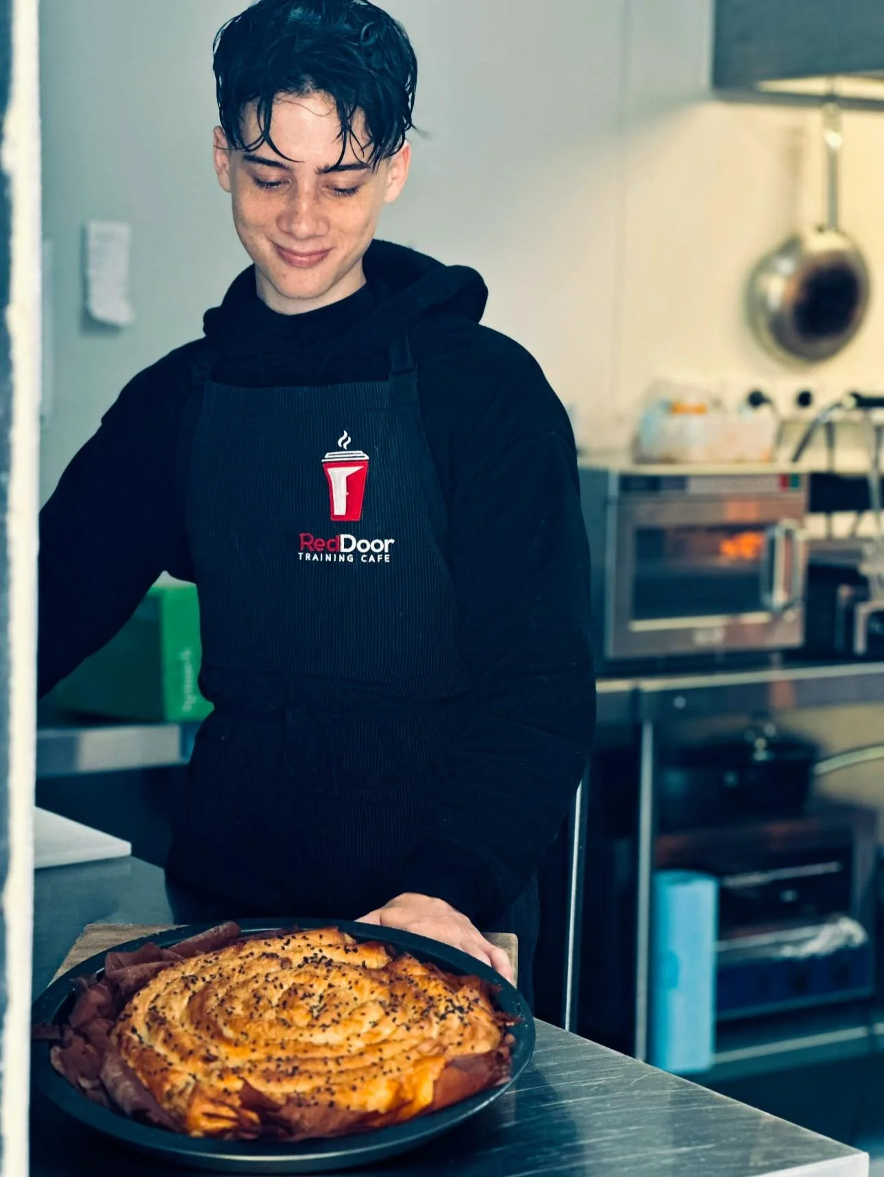 A young person in a RedDoor Training Café apron with fresh baking